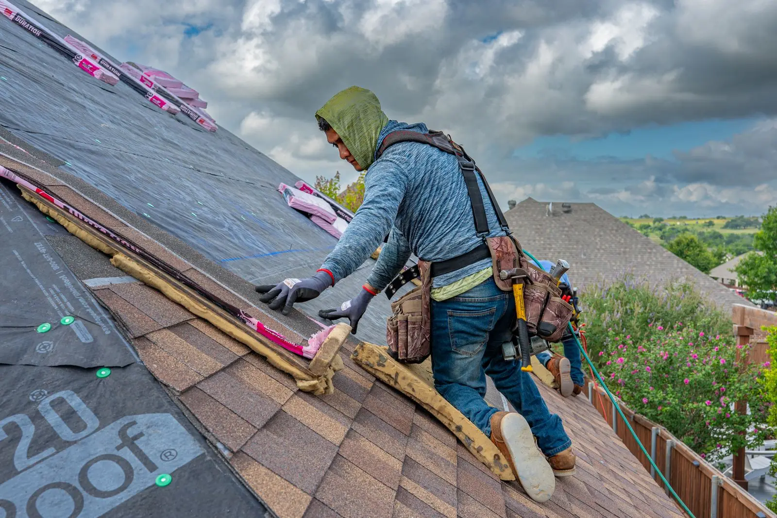 Roofer in a harness working on a pitched shingle roof