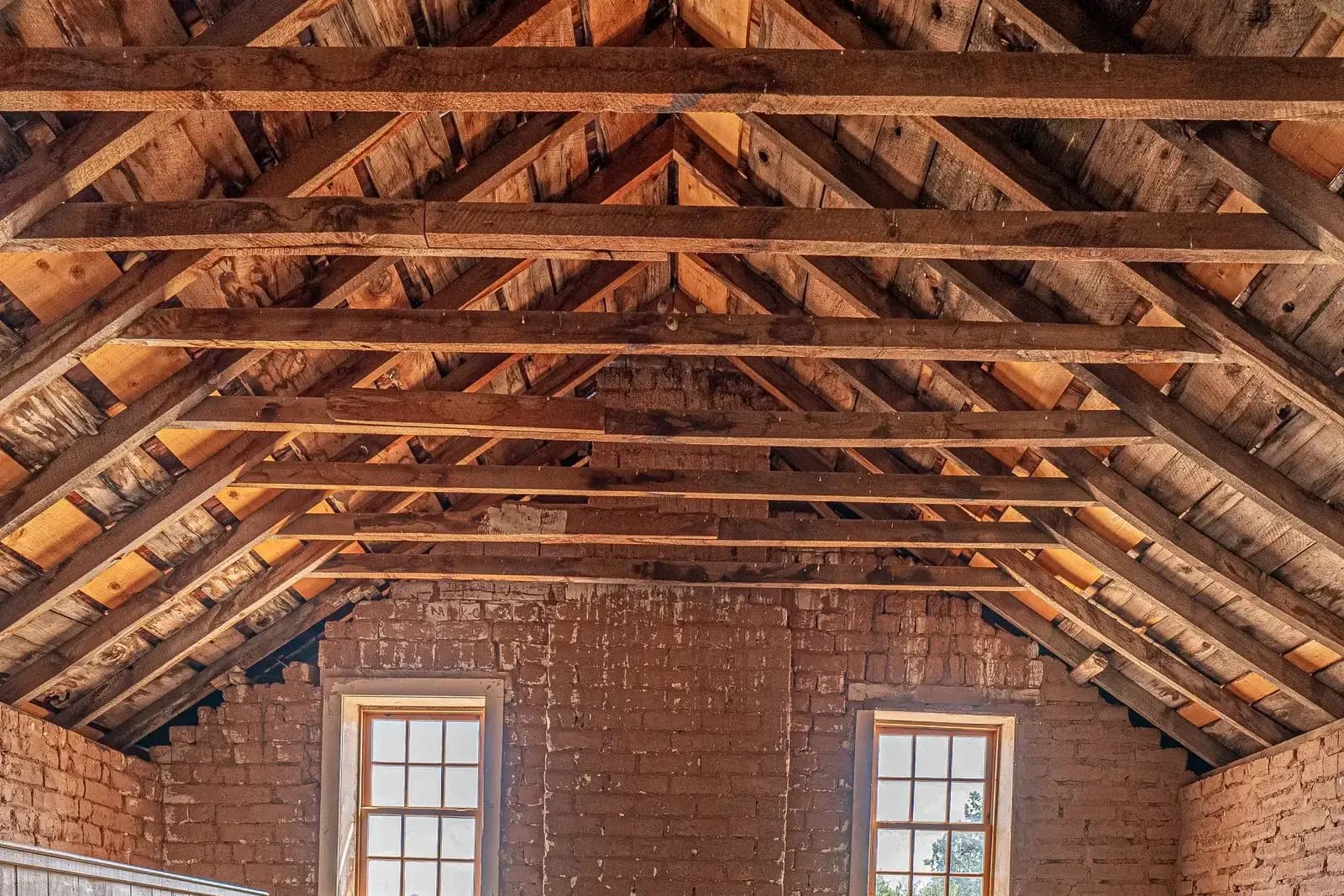 Empty attic with exposed rafters and gable windows