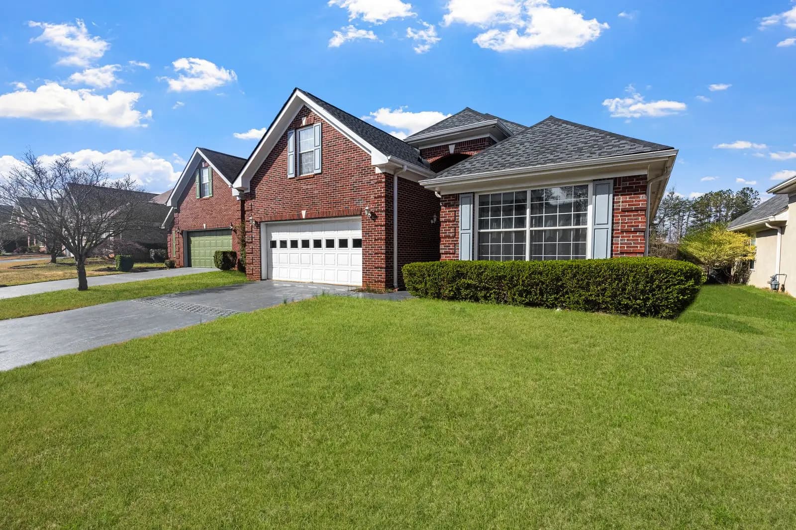 Red brick suburban home with a shingle roof and a wide lawn